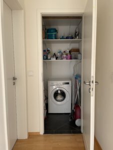 Small storage room including a washing machine in furnished flat in Munich