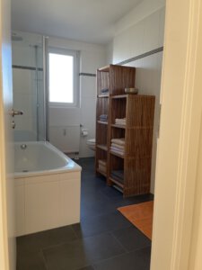 Bathroom with window, bathtub and shower in furnished flat in Munich West