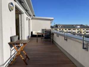 Spacious roof terrace with wooden floorboards and balcony furniture in furnished flat in Munich West